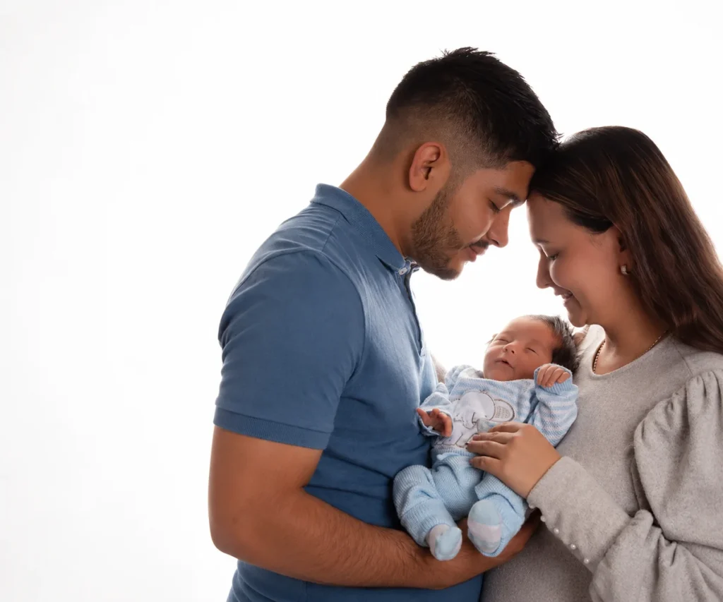 Padres sosteniendo a su bebé recién nacido durante una sesión fotográfica familiar.